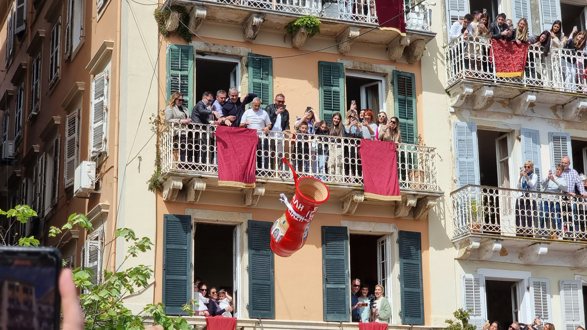 From the balconies above, residents hurl enormous red clay pots - the Botides - downward with all the force they can muster.