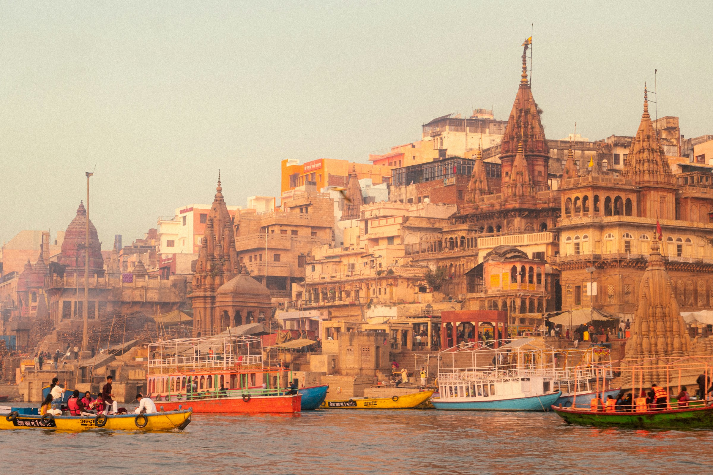 The Ganges River in Varanasi, India, with boats floating calmly and the city’s buildings in the background