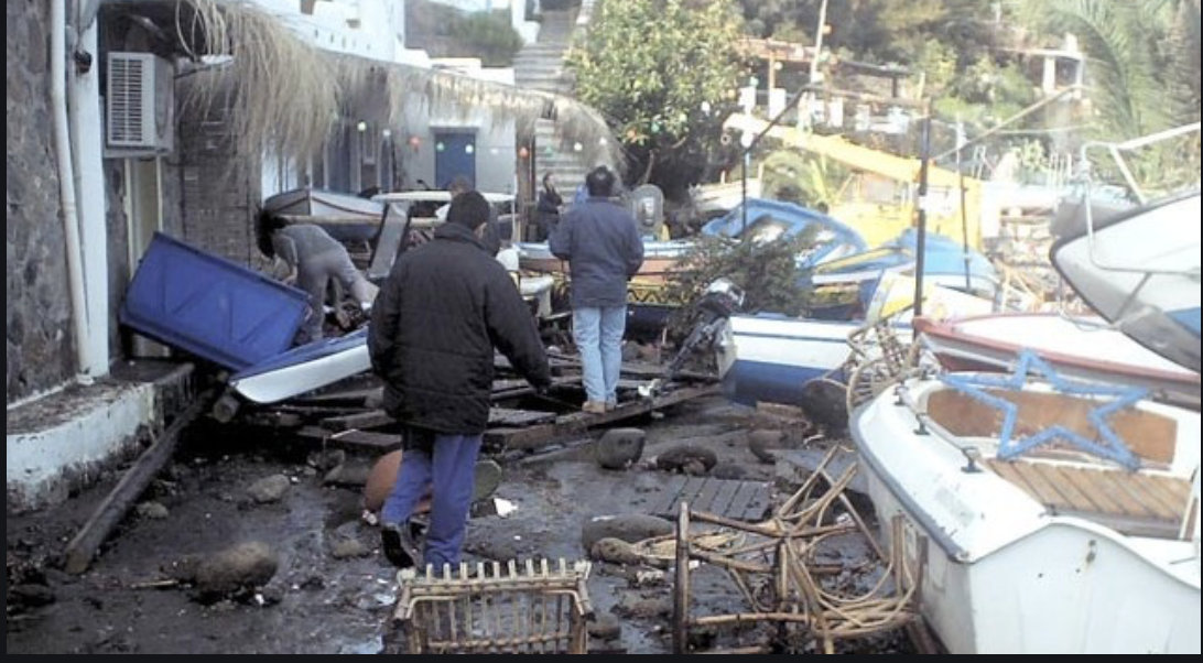 The photo shows people assessing the damage from the tsunami that struck the Italian island of Panarea the day before New Year's Eve in 2002.